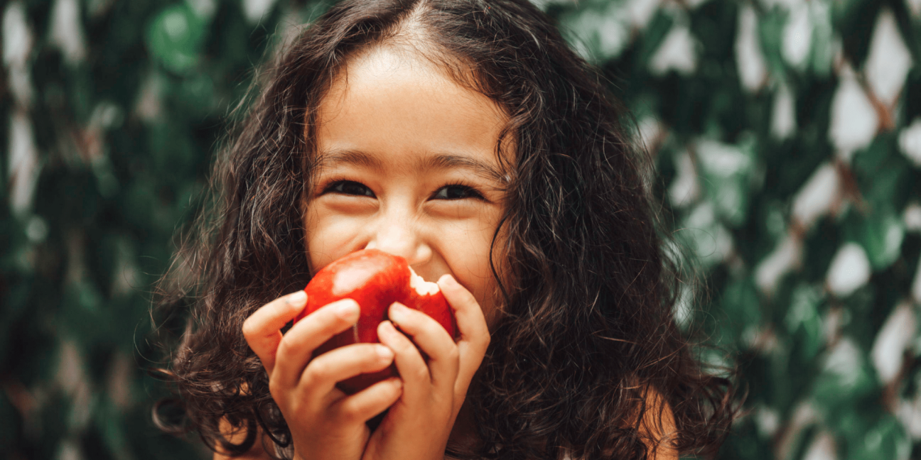 Young girl eating red apple